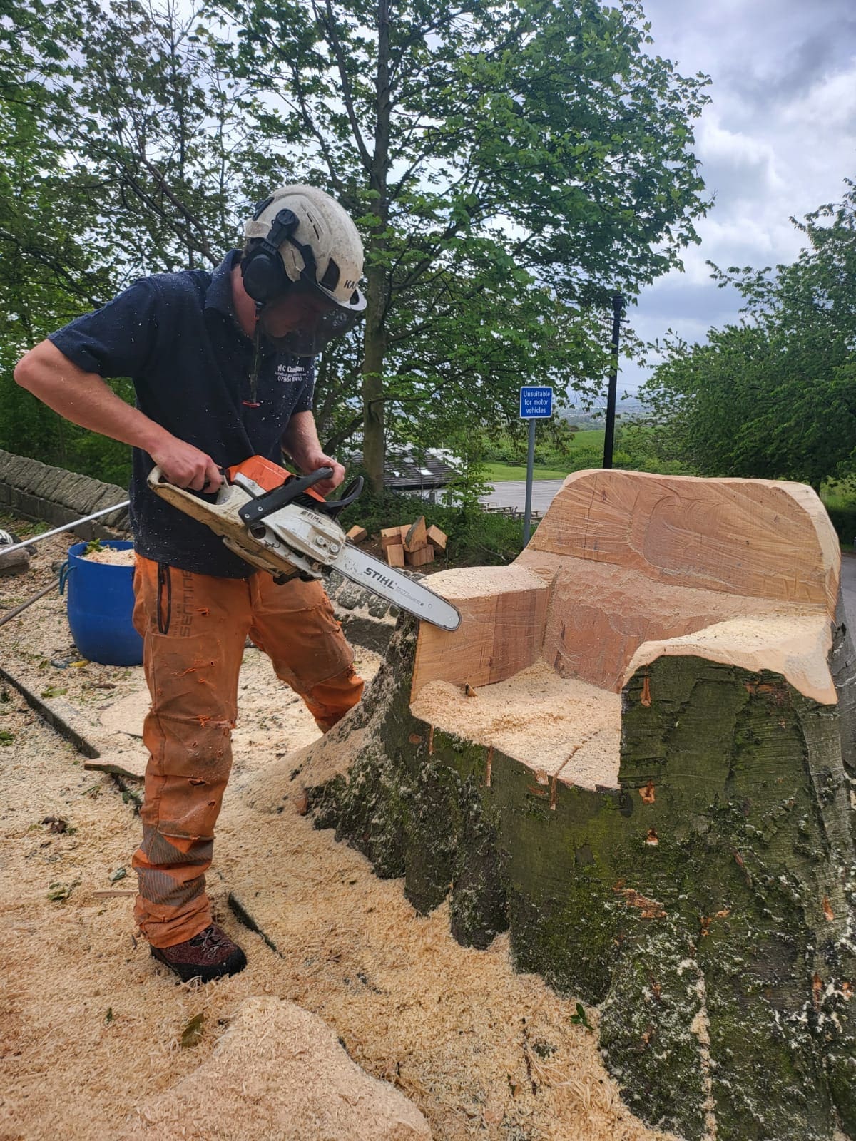 Tree Surgeon carving a chair into a tree stump with a chainsaw